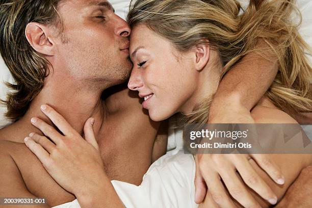 young couple in bed, man kissing woman's forehead, close-up - man and woman kissing in bed stock pictures, royalty-free photos & images