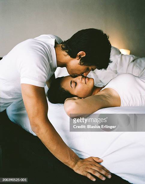 teenage boy (16-18) kissing girl sleeping in bed - romantic young couple sleeping in bed stock pictures, royalty-free photos & images