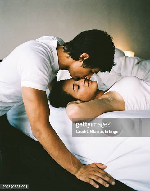 teenage boy (16-18) kissing girl sleeping in bed - couples romance imagens e fotografias de stock