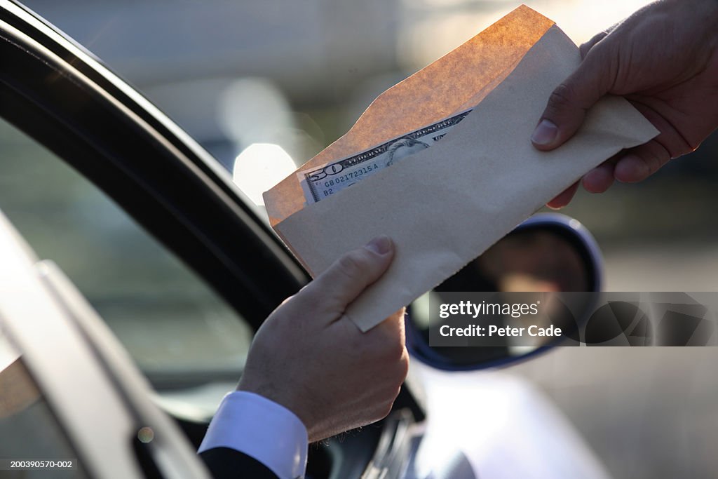 Money being handed over from car, close-up