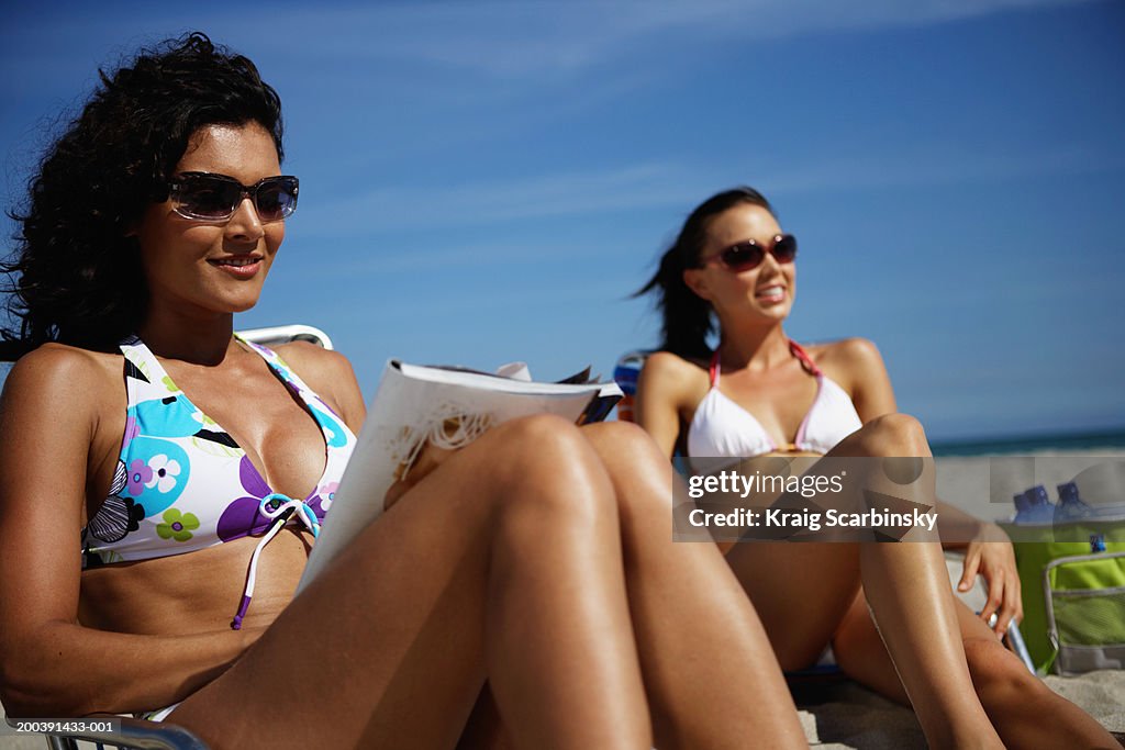 Young woman reading on beach, smiling, close-up