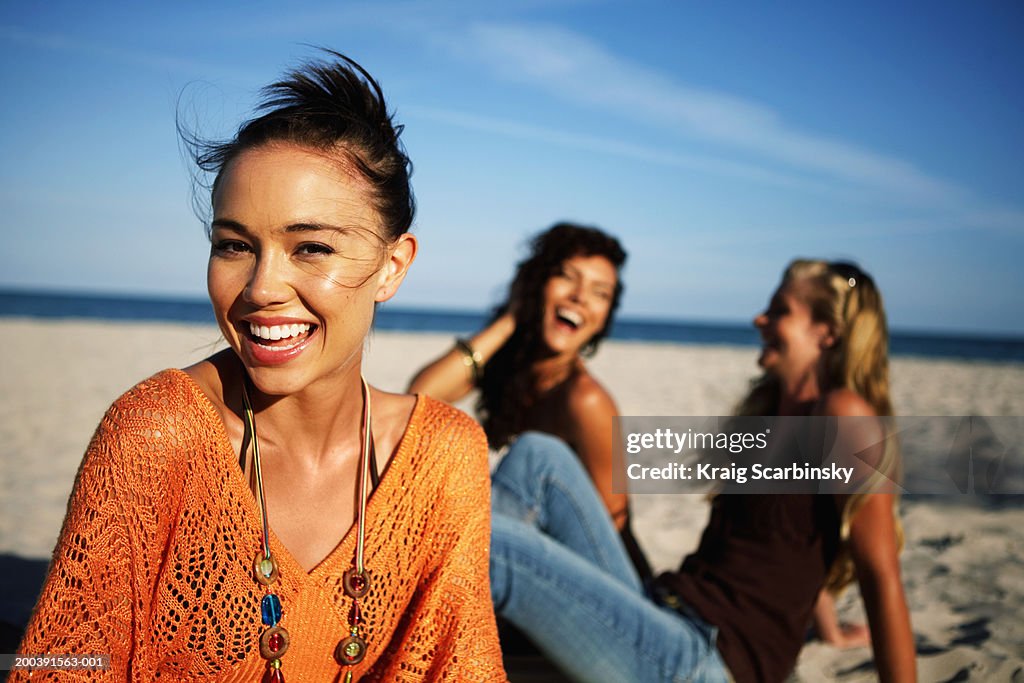 Young women smiling on beach, portrait, close-up (focus on foreground)