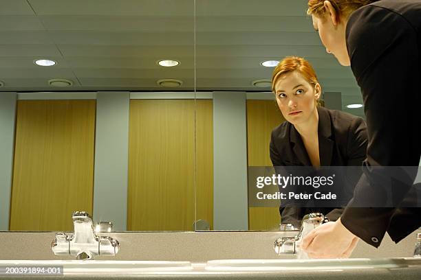 young businesswoman in bathroom, washing hands - public restroom stock-fotos und bilder