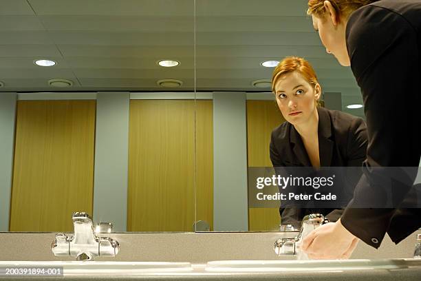 young businesswoman in bathroom, washing hands - mirror reflection stock pictures, royalty-free photos & images