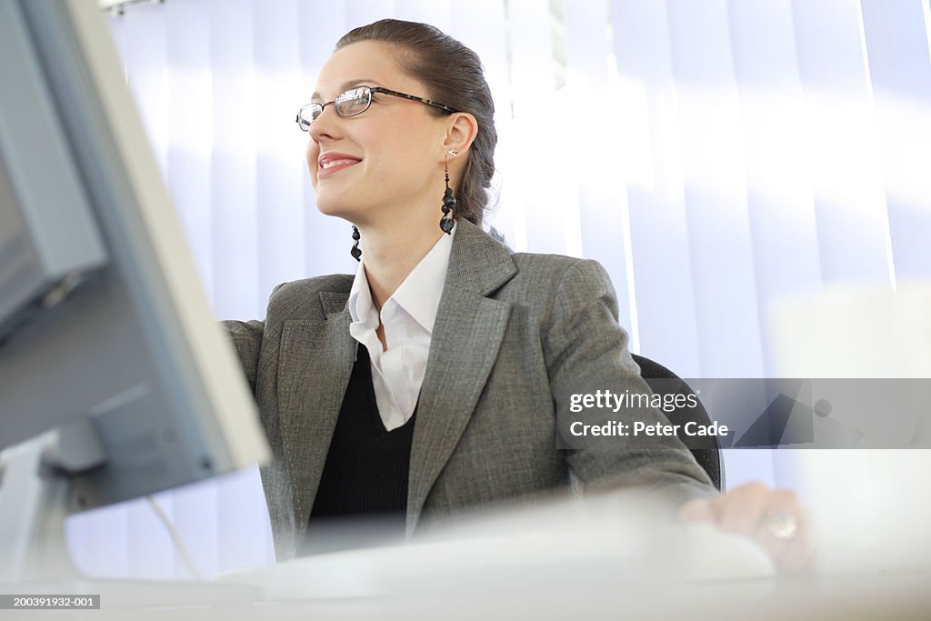 Woman in office working at desk, side view