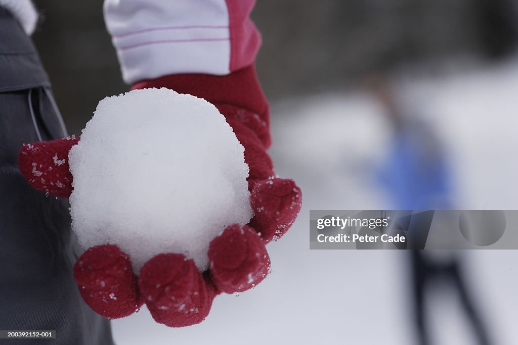 Woman holding a snowball, mid section, close-up