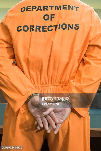 man wearing prisoner uniform, rear view - hands behind back stock photos et images de collection