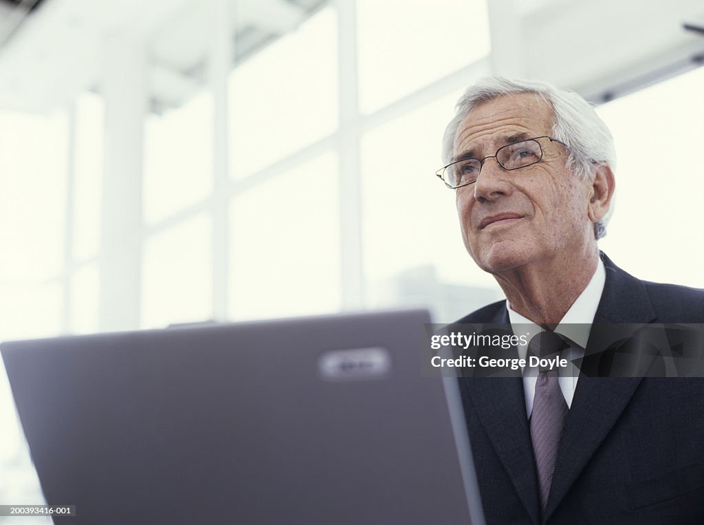 Businessman using laptop, looking away