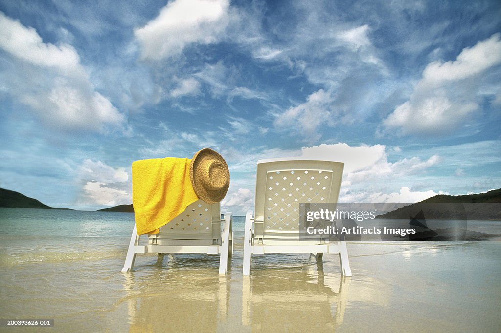 Chairs on beach with towel and hat