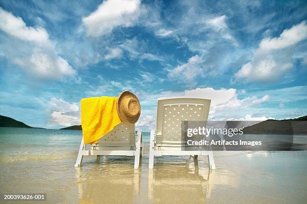 chairs on beach with towel and hat - strandhanddoek stockfoto's en -beelden