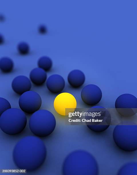 yellow glowing ball among several blue balls - individualidad fotografías e imágenes de stock