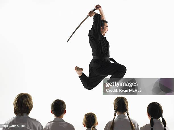 kempo karate instructor jumping in air with sword in front of students - karate stock pictures, royalty-free photos & images