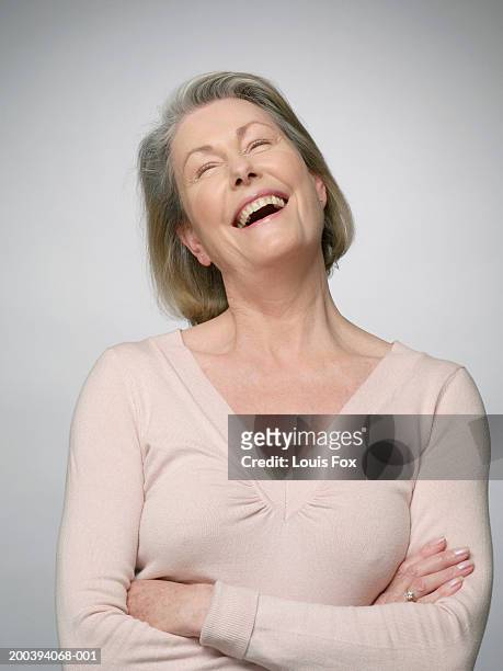 mature woman laughing, arms crossed, eyes closed - neckline stock pictures, royalty-free photos & images
