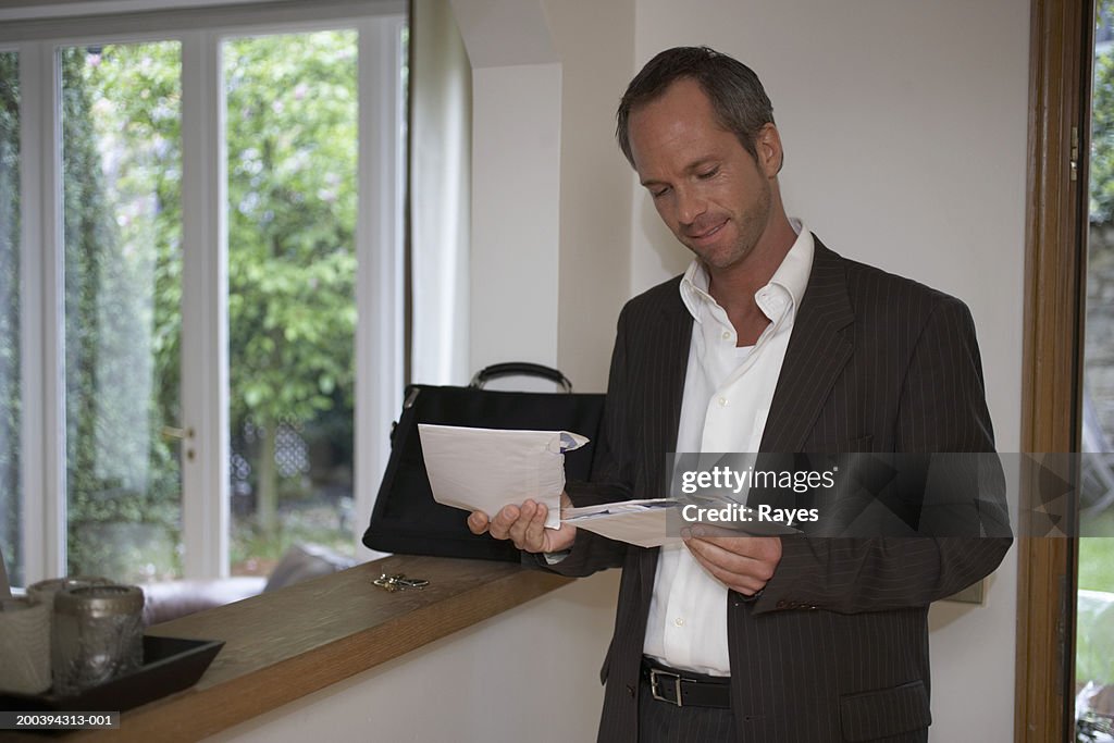 Man standing in hallway looking at post, smiling