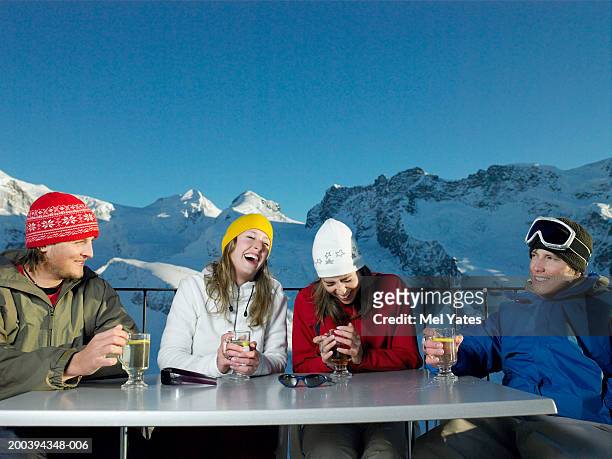 group of friends having drinks outdoors, snowy mountains in background - apres ski imagens e fotografias de stock