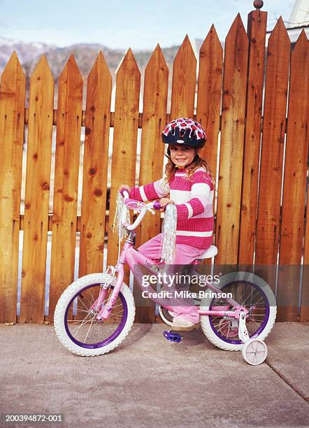 girl (2-4) wearing safety helmet, riding pink bicycle - stützrad stock-fotos und bilder