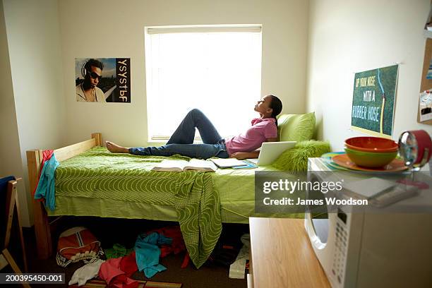 young woman lying on bed in dorm room, side view - girls barefoot in jeans fotografías e imágenes de stock