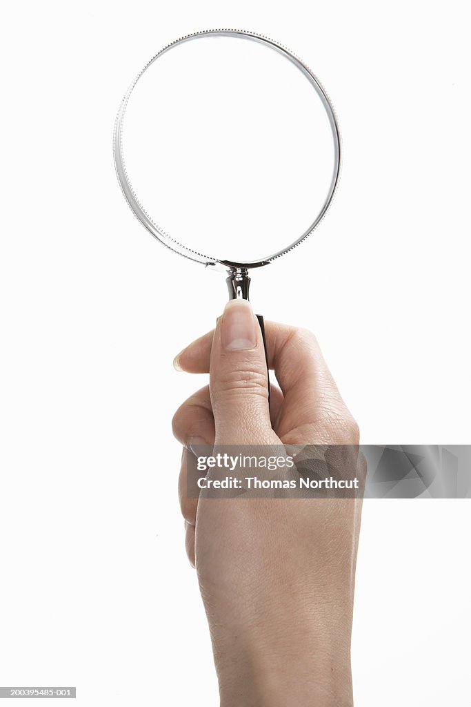 Woman holding magnifying glass (focus on magnifying glass)