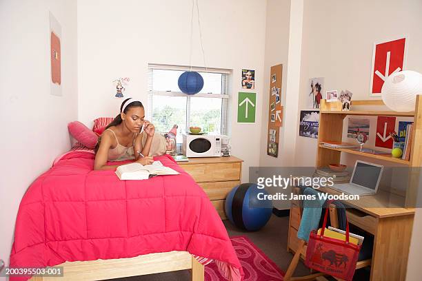 young woman using mobile phone on bed in dorm room - 寮の部屋 ストックフォトと画像