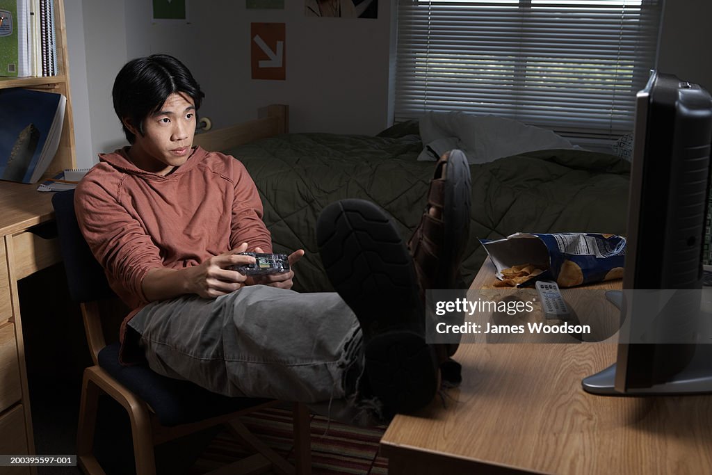 Young man playing video game in dorm room, close-up