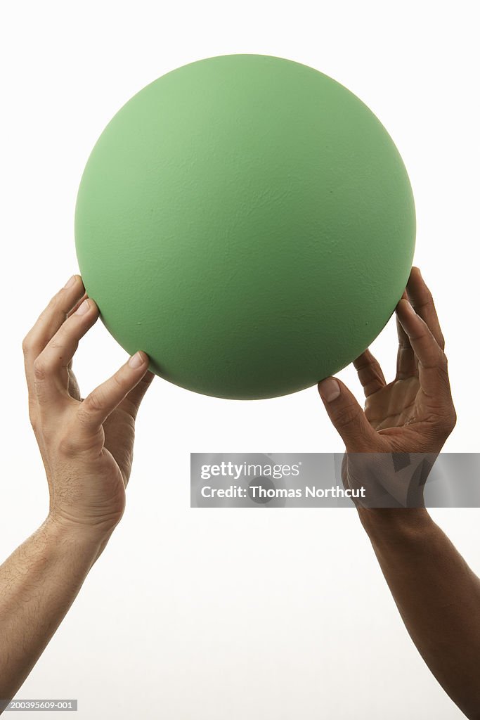 Two people holding up ball (focus on ball)