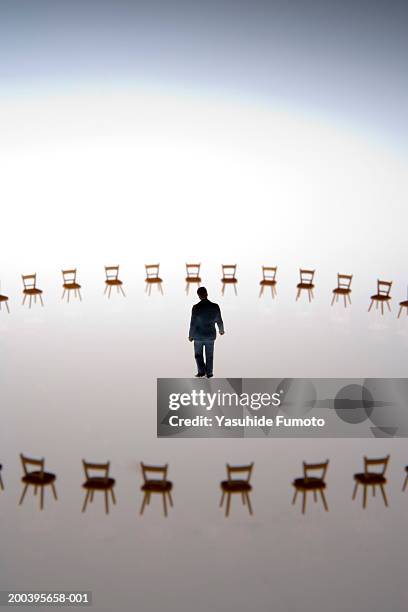 model businessman in center of circle of miniature chairs, rear view - surrounding stock pictures, royalty-free photos & images