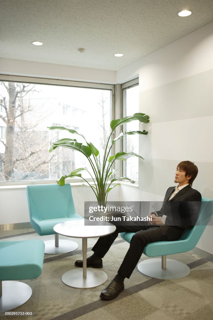 Businessman sitting in office lobby, elevated view