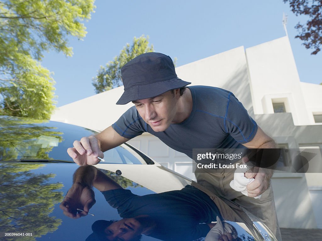Young man cleaning car with cotton bud, clsoe-up