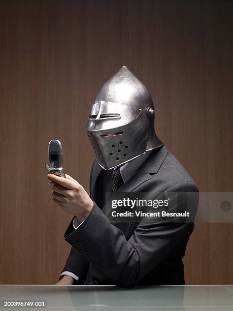 businessman man wearing knight helmet, holding mobile phone - armoured fotografías e imágenes de stock