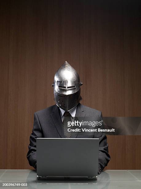 businessman man wearing knight helmet, using laptop - armadura fotografías e imágenes de stock