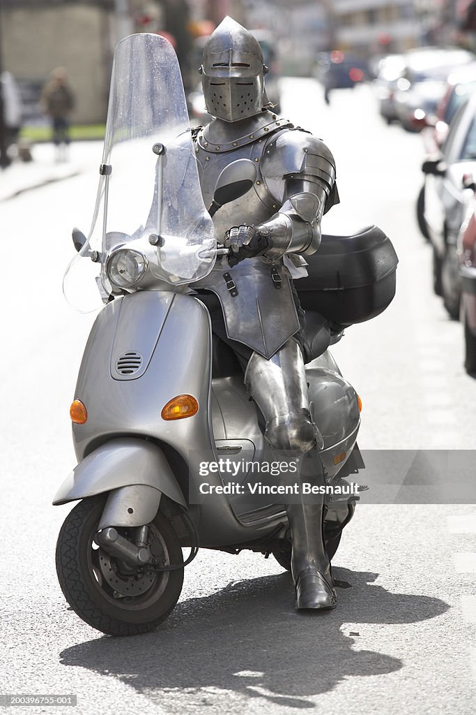 Man wearing knight armour on moped
