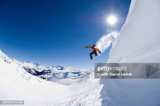 male snowboarder jumping off cornice, low angle view - snowboard stockfoto's en -beelden