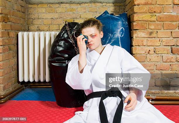 young woman with black eye wearing gi - black eye stockfoto's en -beelden