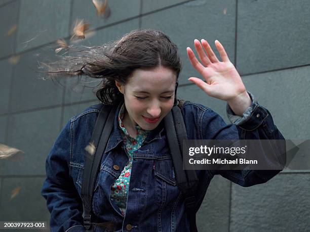 young woman shielding face from wind, eyes closed, close-up - wind photos et images de collection