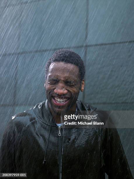 young man standing in rain, eyes tightly closed, close-up - hood clothing stock pictures, royalty-free photos & images