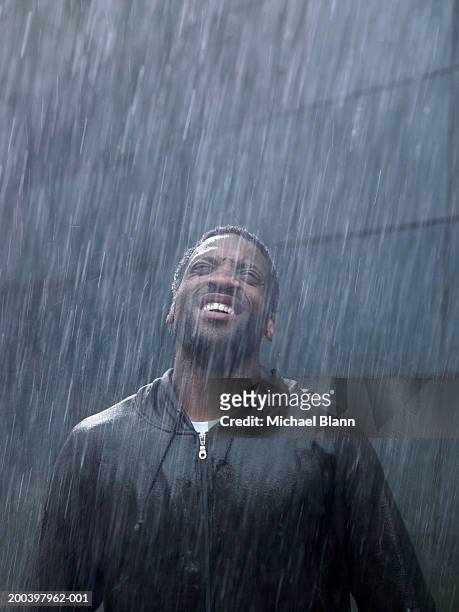 young man standing in rain, head back, looking up - torrential rain stock pictures, royalty-free photos & images