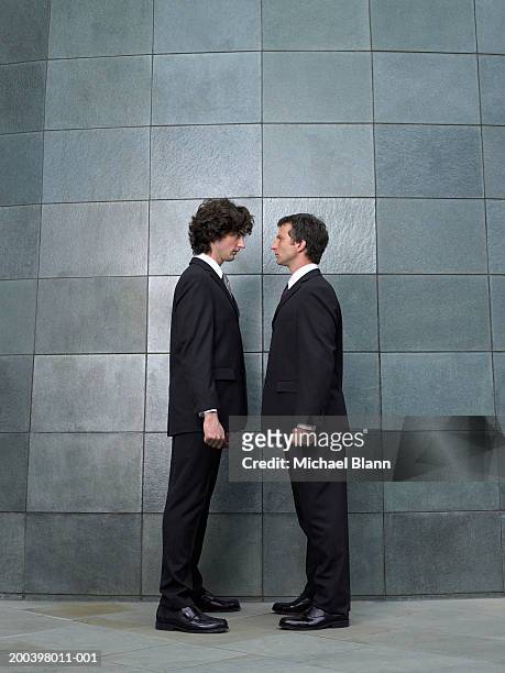 two businessmen standing face to face, side view - diverbio foto e immagini stock