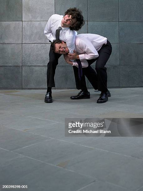 two businessmen fighting, younger man holding colleague in headlock - headlock stock pictures, royalty-free photos & images