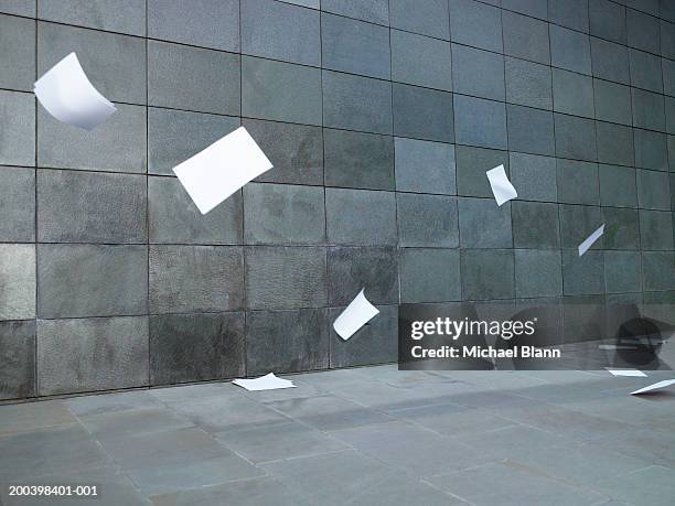 pieces of paper blowing along street - windy city stock pictures, royalty-free photos & images