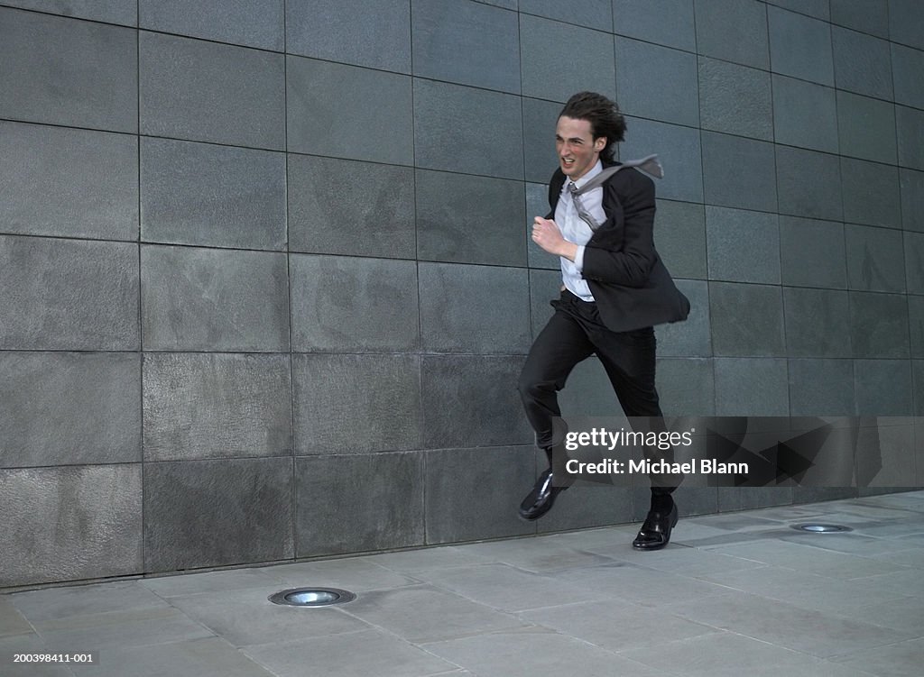 Young businessman running against wind