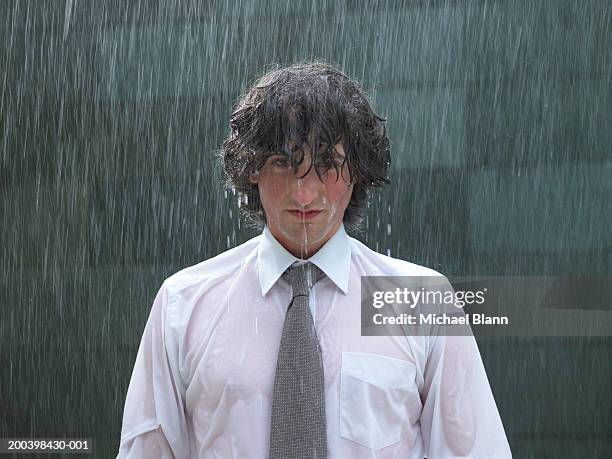 young businessman standing in rain, portrait, close-up - nass stock-fotos und bilder