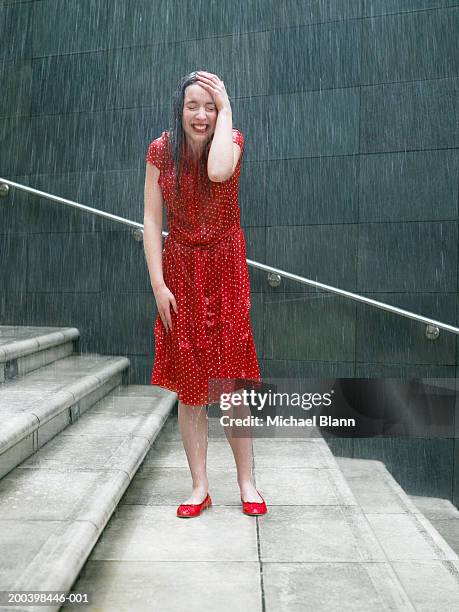 young woman on steps in rain, hand resting on head, eyes closed - fuktighet bildbanksfoton och bilder