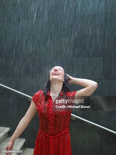 young woman leaning back on steps in rain, hand behind head - rain smiling stock-fotos und bilder