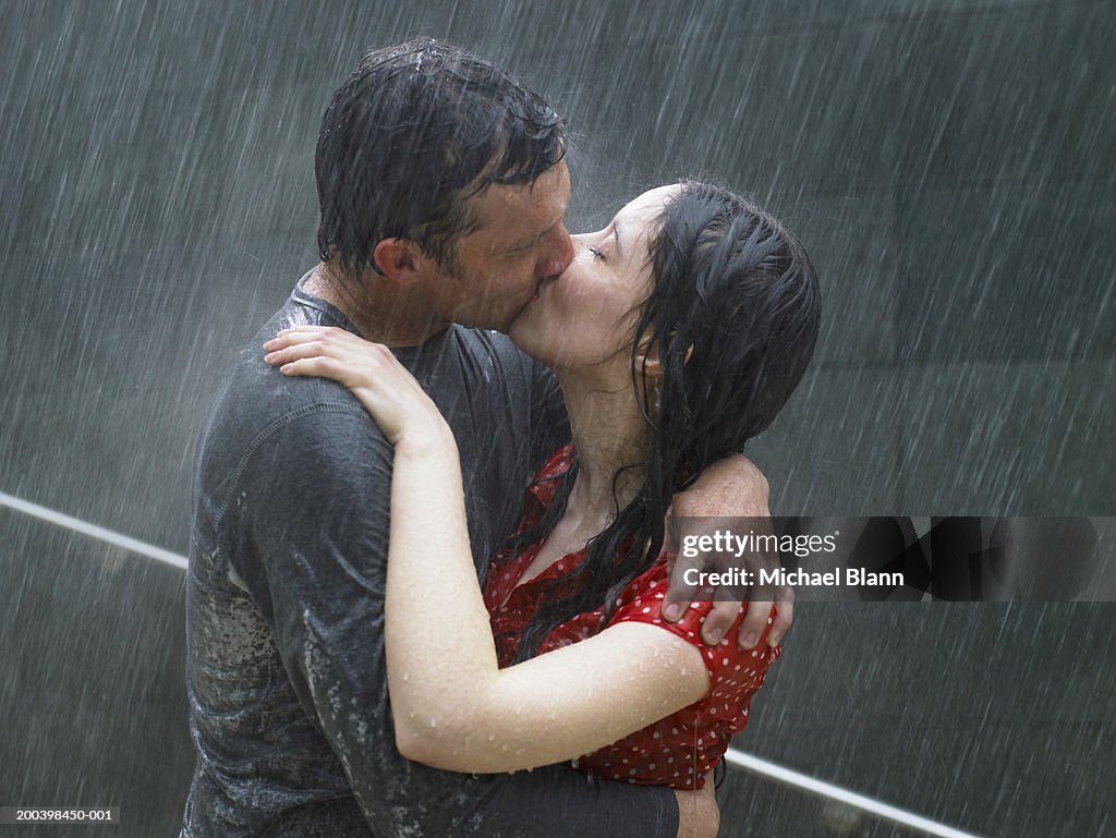 Couple kissing in rain, side view, close-up