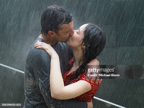 couple kissing in rain, side view, close-up - der kuss stock-fotos und bilder