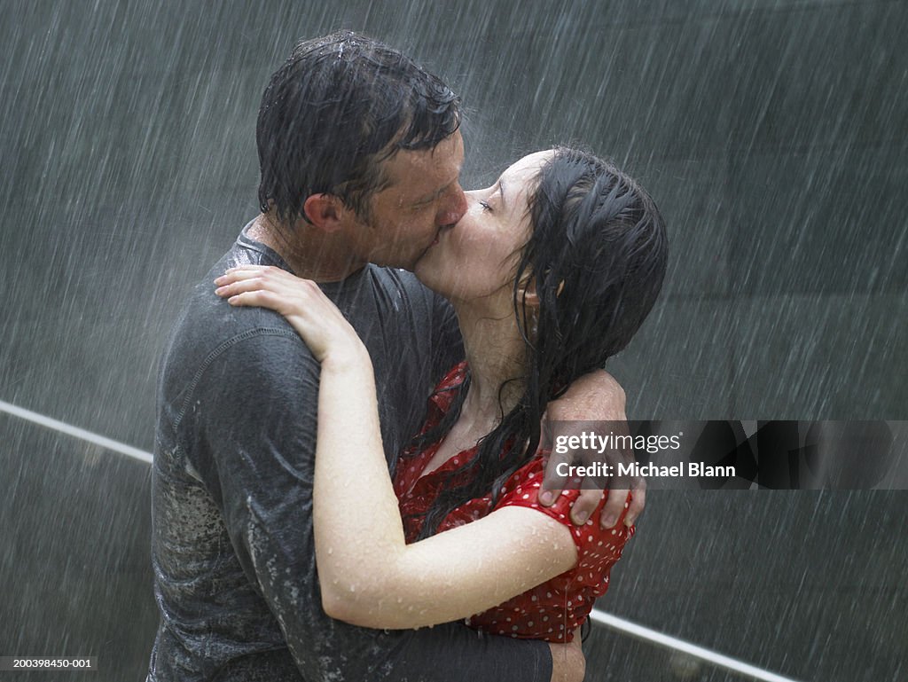 Couple kissing in rain, side view, close-up