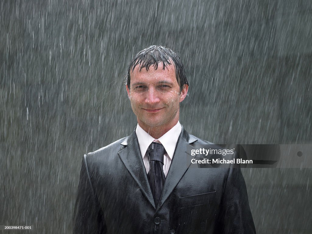 Homme d'affaires debout sous la pluie, souriant, portrait, gros plan