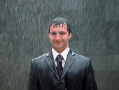 Businessman standing in rain, smiling, portrait, close-up