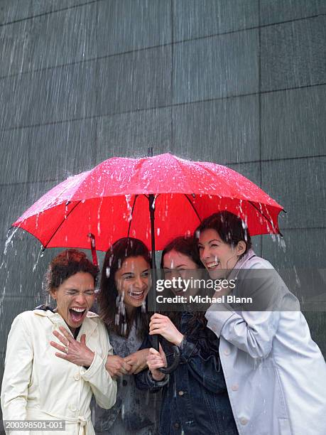 four women sharing umbrella in rain, laughing - sheltering stock pictures, royalty-free photos & images