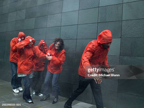 group of people in anoraks struggling to walk against wind - kagoul stock pictures, royalty-free photos & images